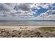 Picturesque view of a sandy beach with calm water and a cloudy sky backdrop at 14459 River Beach Dr # 218, Port Charlotte, FL 33953