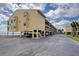 Low-angle exterior view of a yellow condo building with covered parking and waterfront views at 14459 River Beach Dr # 218, Port Charlotte, FL 33953