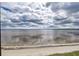 Stunning waterfront view showcases a calm bay, sandy beach, and cloudy sky, offering a serene and picturesque scene at 14459 River Beach Dr # 218, Port Charlotte, FL 33953