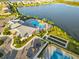 Stunning aerial view of a pool, lake, clubhouse, tennis court, and bocce ball in a beautiful community at 17610 Polo Trl, Bradenton, FL 34211