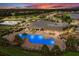 Aerial view of community featuring a sparkling pool, clubhouse, playground, and tennis courts at dusk at 17610 Polo Trl, Bradenton, FL 34211