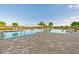 Inviting pool area with comfortable lounge chairs, tropical palm trees, and a serene lake view at 17610 Polo Trl, Bradenton, FL 34211
