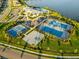Aerial view of multiple tennis courts, a basketball court, and surrounding amenities near a beautiful lake at 17610 Polo Trl, Bradenton, FL 34211