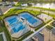 Aerial view of well-maintained community tennis and basketball courts next to a scenic lake and walking paths at 17610 Polo Trl, Bradenton, FL 34211