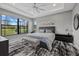 Spacious bedroom featuring tray ceilings, a ceiling fan, and an expansive window overlooking the landscaped backyard at 17814 Cresswind Ter, Bradenton, FL 34211