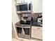 Close up view of stainless steel oven, cooktop, tile backsplash, and overhead microwave at 2057 Sunset Dr # G1, Bradenton, FL 34207