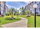 A lush pathway runs through well-maintained landscaping between condominium buildings, under a bright blue sky at 250 Santa Maria St # 215, Venice, FL 34285