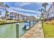 Waterfront condo featuring dock and boat with a blue cover, under a sunny sky, complete with lush landscaping at 250 Santa Maria St # 215, Venice, FL 34285