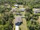 An aerial view of a home with a well manicured lawn and a fenced in backyard surrounded by green trees at 2721 Burri Ter, North Port, FL 34288