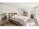 Neutral bedroom with natural wood bed frame, matching side table, and dresser with a view to the ensuite bath at 2721 Burri Ter, North Port, FL 34288