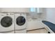 Clean laundry room with sink, counter, and ample cabinet storage with modern white appliances at 280 Golden Gate Pt # 400, Sarasota, FL 34236