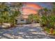 Charming single-story home featuring a gravel driveway, lush landscaping, and vibrant tropical foliage at 3086 Pinecrest St, Sarasota, FL 34239