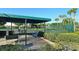 Shaded tennis court and seating area surrounded by lush greenery and mature palms at 3540 Mistletoe Ln, Longboat Key, FL 34228