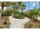 Backyard with a fork in the pea gravel path surrounded by tropical landscaping and palm trees at 3595 Shamrock Dr, Venice, FL 34293