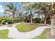 Lush backyard with palm trees features winding gravel pathways, leading to a seating area with a firepit at 3595 Shamrock Dr, Venice, FL 34293