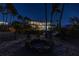 Spacious backyard with a fire pit, Adirondack chairs, hammock, and palm trees at night at 3935 N Shell Rd, Sarasota, FL 34242