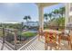 Beautiful waterfront balcony with an outdoor table set, offering scenic views of the water and palm trees at 3935 N Shell Rd, Sarasota, FL 34242
