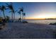 Sunset view from the beach with palm trees, blue beach chairs, and soft sandy beach at 3935 N Shell Rd, Sarasota, FL 34242