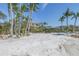 A picturesque beachfront property with white sand and palm trees framing a luxurious home at 3935 N Shell Rd, Sarasota, FL 34242