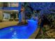 Tranquil pool at night with ambient lighting, waterfall, and lush tropical landscaping at 3935 N Shell Rd, Sarasota, FL 34242