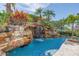 Inviting pool features a rock waterfall, lush plants and palm trees at 3935 N Shell Rd, Sarasota, FL 34242