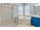 Bright bathroom features a glass shower, soaking tub, blue cabinets, and neutral tile throughout at 428 Islebay Dr, Apollo Beach, FL 33572