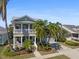 Charming two-story coastal home with a covered front porch, a second-story balcony, mature palm trees, and an attached two-car garage at 428 Islebay Dr, Apollo Beach, FL 33572