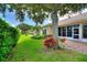 View of the backyard patio, with lush green lawn, screened in lanai, and privacy landscaping at 4790 Turnberry Cir, North Port, FL 34288
