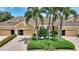 Exterior view of home with a brick driveway, manicured landscaping, and mature palm trees at 4790 Turnberry Cir, North Port, FL 34288