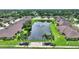 Community pond with a water fountain, surrounded by palm trees, lush grass and homes at 4790 Turnberry Cir, North Port, FL 34288