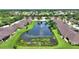 Aerial view of a community pond with lush green grass and a fountain in the center at 4790 Turnberry Cir, North Port, FL 34288