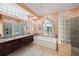 Luxurious bathroom with double vanity, soaking tub, glass block accents, and a separate shower at 6107 Glen Abbey Ln, Bradenton, FL 34202