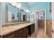 Modern bathroom with dual sinks, granite countertop, decorative mirrors, and tiled floors at 6107 Glen Abbey Ln, Bradenton, FL 34202