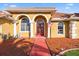 Charming house front with a striking red door, decorative windows, pillars, and manicured front yard at 6107 Glen Abbey Ln, Bradenton, FL 34202