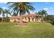 Expansive front yard featuring a well-manicured lawn, mature palm trees, and a charming yellow single-story home at 6107 Glen Abbey Ln, Bradenton, FL 34202