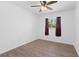 Cozy bedroom with hardwood floors, ceiling fan, and a large window with maroon curtains at 7018 13Th E Ave, Bradenton, FL 34208