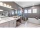 Bright bathroom featuring double vanities, a soaking tub, and a glass-enclosed shower with elegant fixtures at 7928 Redonda Loop, Bradenton, FL 34202