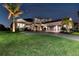 Nighttime shot of a home exterior featuring a well-kept lawn, lush landscaping, and brick paved driveway at 7928 Redonda Loop, Bradenton, FL 34202