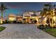 Elegant home featuring a well manicured lawn, paved driveway and mature tropical landscaping at dusk at 7928 Redonda Loop, Bradenton, FL 34202