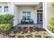 Inviting porch with wicker chairs and a small table, framed by colorful landscaping at 7928 Redonda Loop, Bradenton, FL 34202