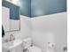 Stylish half-bath with white wainscoting, blue accent wall, and modern fixtures at 7928 Redonda Loop, Bradenton, FL 34202