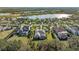 Panoramic aerial view of a grand home with a tile roof, surrounded by green lawns, and a tranquil lake at 8455 Lindrick Ln, Bradenton, FL 34202