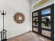 Inviting entryway features modern black double doors with a sunburst mirror and light wood floors at 8455 Lindrick Ln, Bradenton, FL 34202