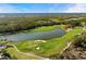 Picturesque aerial view of a lush green golf course featuring a scenic pond and sand traps at 8455 Lindrick Ln, Bradenton, FL 34202