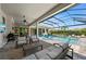 A covered outdoor living area with a pool, patio furniture, summer kitchen and lush landscaping, perfect for relaxing at 8455 Lindrick Ln, Bradenton, FL 34202