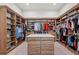 Spacious walk-in closet with custom wood shelving, storage, and a center island with drawers, providing ample wardrobe space at 8455 Lindrick Ln, Bradenton, FL 34202