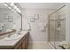 Bathroom featuring double sinks, framed mirrors, granite counters, and a glass-enclosed shower with tiled accents at 8928 Excelsior Loop, Venice, FL 34293