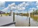 Clean waterfront dock with wooden pilings on a serene canal, surrounded by green vegetation at 10494 Atenia St, Port Charlotte, FL 33981