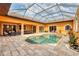 Aerial view of a screened-in pool with a hot tub, patio furniture, outdoor dining, and colorful orange exterior walls at 10494 Atenia St, Port Charlotte, FL 33981