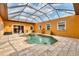 Screened-in pool with hot tub surrounded by travertine pavers and colorful orange exterior walls at 10494 Atenia St, Port Charlotte, FL 33981